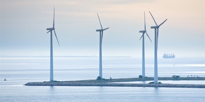 Wind turbines standing on the shore by the ocean